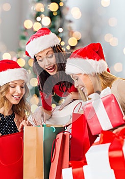 Smiling young women in santa hats with gifts