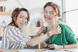 smiling young women trying on handmade necklace