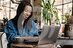 Smiling yuong african woman working on laptop