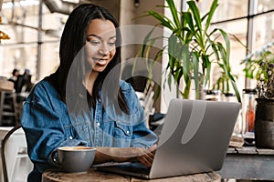 Smiling yuong african woman working on laptop