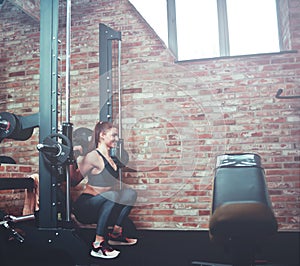 Smilling athletic woman exercising squatting with barbell