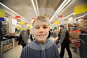 Smilling boy stand in centre in supermarket