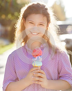Smilling girl holding ice cream cone in her hands outdoors