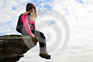 Smilling girl sitting on a rock.