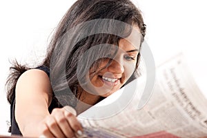 Smilling indian teen reading newspaper