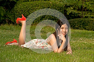 Smilling pretty Asian woman pose of lying on a lawn in the park