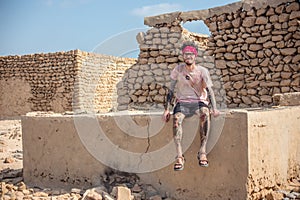 Smilling young man sitting at the acient ruins of the persian village
