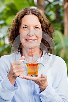 Smilng mature woman drinking herbal tea