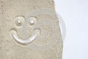 Smily face drawn on sand in white isolated background