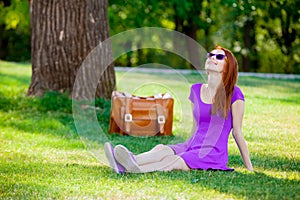 Smily redhead girl in sunglasses with suitcase