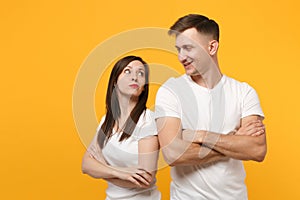 Smirked young couple two friends guy girls in white blank empty design t-shirts posing isolated on yellow orange wall