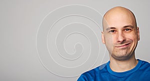 Smirking bald guy isolated on gray