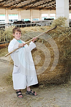 Smling boy in white coat loads hay by big