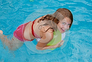 Smling girl holding a beach ball in a swimming pool