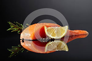 Smocked salmon with rosemary, lemon, and peppercorn on a black background