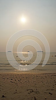 Smog obscures sun's rays. People relax on beach