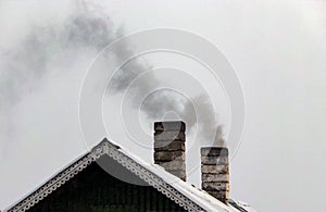 Smoke billows from the house`s chimneys. Furnace heating of the house.