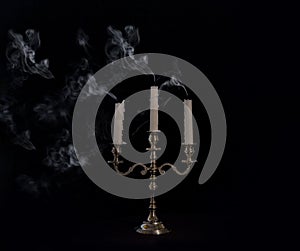 Smoke from a burning candle in candelabra on a black background