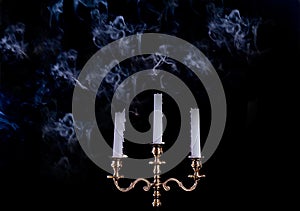 Smoke from a burning candle in candelabra on a black background