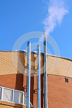 Smoke from a chimney on blue sky background.