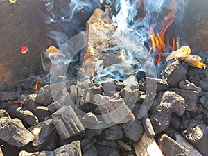 Smoke of the coal on the embers. Preparation of fire for barbecue embers. Outdoor recreation. Flames seen in the image