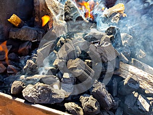 Smoke of the coal on the embers. Preparation of fire for barbecue embers. Outdoor recreation. Flames seen in the image