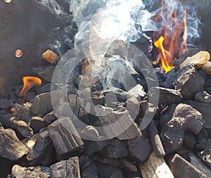 Smoke of the coal on the embers. Preparation of fire for barbecue embers. Outdoor recreation. Flames seen in the image