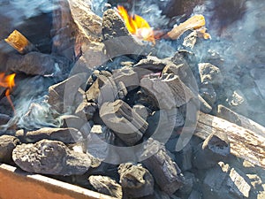 Smoke of the coal on the embers. Preparation of fire for barbecue embers. Outdoor recreation. Flames seen in the image