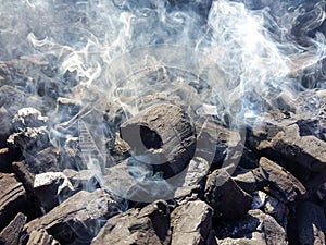 Smoke of the coal on the embers. Preparation of fire for barbecue embers. Outdoor recreation. No flames seen in the image