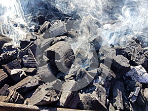 Smoke of the coal on the embers. Preparation of fire for barbecue embers. Outdoor recreation. No flames seen in the image