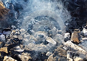 Smoke of the coal on the embers. Preparation of fire for barbecue embers. Outdoor recreation. No flames seen in the image
