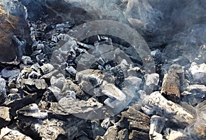 Smoke of the coal on the embers. Preparation of fire for barbecue embers. Outdoor recreation. No flames seen in the image