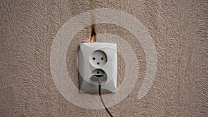 Smoke comes from a faulty outlet in the apartment. The concept of the start of a fire in the house. Overheating of the