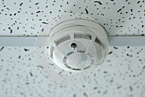 Smoke detector mounted on plain ceiling, fire alarm system.