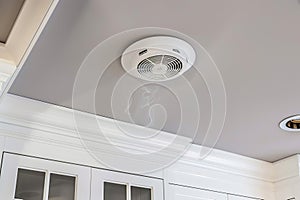 Smoke detector on white ceiling in modern kitchen interior for safety and fire prevention