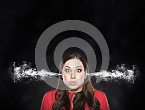 Smoke from the ears of a woman over dark background.