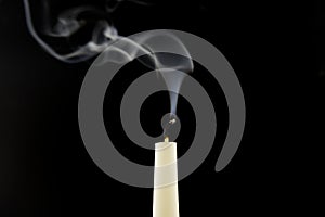 White candle extinguished on black background