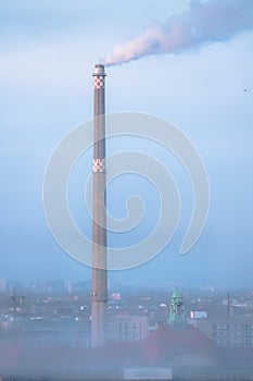 Smoke from a factory chimney in a hazy urban sky