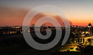 Smoke from a fire over a night city on a sunset sky in Rome, Italy