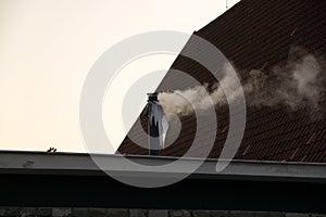 Smoke going from chimney with icicles during sunny cold winter day.