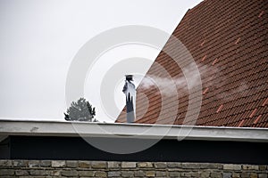 Smoke going from chimney with icicles during sunny cold winter day.