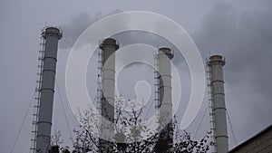 Smoke industrial pipes on a background of gray cloudy sky. Smoke from the chimneys of a plant against a gray sky. Environmental