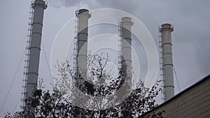 Smoke industrial pipes on a background of gray cloudy sky. Smoke from the chimneys of a plant against a gray sky. Environmental