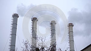 Smoke industrial pipes on a background of gray cloudy sky. Smoke from the chimneys of a plant against a gray sky. Environmental