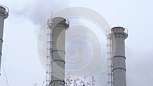 Smoke industrial pipes on a background of gray cloudy sky. Smoke from the chimneys of a plant against a gray sky. Environmental