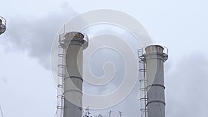 Smoke industrial pipes on a background of gray cloudy sky. Smoke from the chimneys of a plant against a gray sky. Environmental