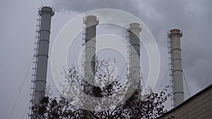 Smoke industrial pipes on a background of gray cloudy sky. Smoke from the chimneys of a plant against a gray sky. Environmental