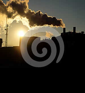 Smoke from power plant chimney at sunset backlit toned image