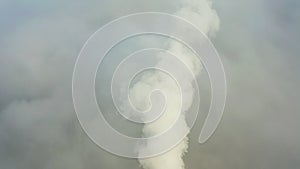 Smoke from a power station chimney rising from a low, creeping fog. Drone view