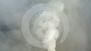 Smoke from a power station chimney rising from a low, creeping fog. Drone view